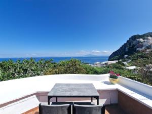 - stół i krzesła na balkonie z widokiem na ocean w obiekcie Il Cantuccio Rooms w mieście Capri