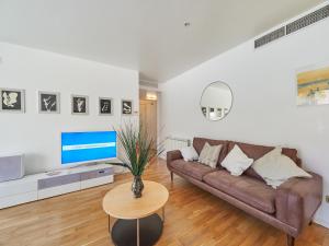 un soggiorno con divano marrone e TV di Barcelonaforrent Vila Olimpica Pool Suites a Barcellona