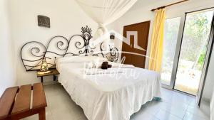 a bedroom with a white bed with a large headboard at MiRADOR DEL FARO in Cala en Bosc