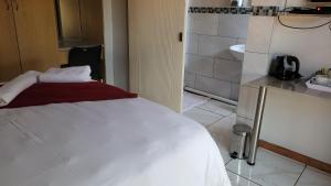 a bedroom with a white bed and a bathroom at Pab-Love Guest House in Kuruman