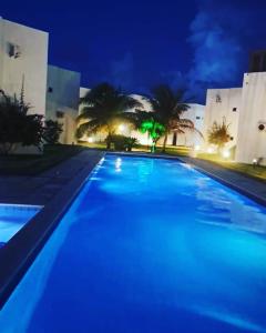 a large swimming pool at night with blue lights at Chalé Paraíso -Maracajaú 4- Casa 38 - Beira-mar in Maxaranguape