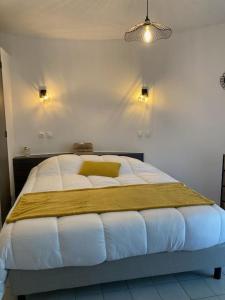 um quarto com uma cama grande com lençóis brancos e almofadas amarelas em La Geck'home em Le Barcarès