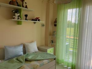 a bedroom with a bed with green curtains and a window at Alexandra's House Nea Fokaia in Nea Fokea