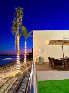 杜拉艾列拉巴斯的住宿－شاليهات كابري وماديرا درة العروس，庭院拥有两棵棕榈树和桌椅
