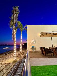 a patio with two palm trees and a table and chairs at شاليهات كابري وماديرا درة العروس in Durat Alarous
