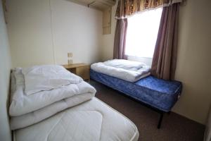 a small room with two beds and a window at 6 Berth Pet Friendly Caravan In Hunstanton By The Beach Ref 13001l in Hunstanton