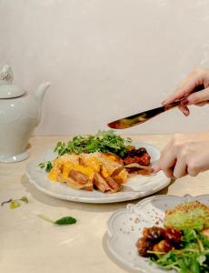 uma pessoa a cortar um prato de comida com uma faca em Tau House em Guatapé