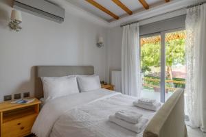 a bedroom with a white bed and a large window at Crystal Beach Villa in Chalkida