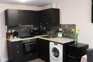 a kitchen with black cabinets and a washing machine at Self-contained guest suite in Eltham