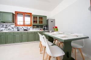 a kitchen with green cabinets and a table with white chairs at Casa del Sole: Relax & Charme nella Riviera Ligure in Camporosso