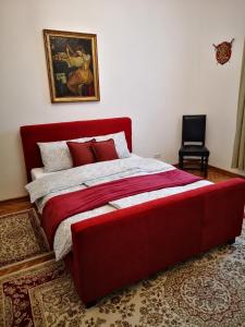 卡雷加多的住宿－Weisz Castle style Apartment - Free Private Parking,Wifi，卧室配有一张红色大床,墙上挂有绘画作品