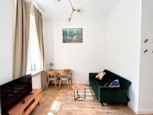 a living room with a green couch and a table at Warsaw Concierge Studio Koszykowa in Warsaw