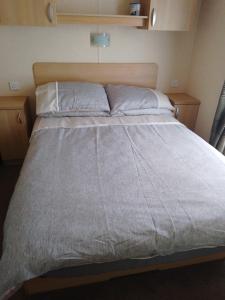 1 dormitorio con 1 cama grande y cabecero de madera en Ocean Heights 5 star site NewQuay, en Llanllwchaiarn