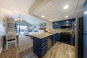 a kitchen with blue cabinets and a bed in the background at Raintree's Park Plaza Park City in Park City