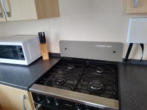 a stove top oven in a kitchen next to a microwave at Ocean Heights 5 star site NewQuay in Llanllwchaiarn