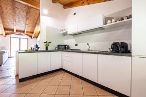 a kitchen with white cabinets and a wooden ceiling at Appartamento Al Forte in Nago-Torbole