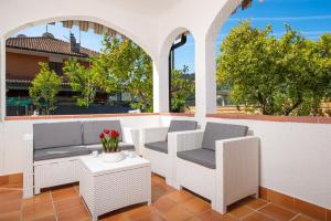 a patio with white wicker chairs and a table at Casa del Sole: Relax & Charme nella Riviera Ligure in Camporosso