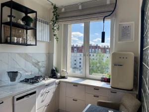 a kitchen with white cabinets and a large window at Słoneczny Apartament Koszykowy! in Warsaw
