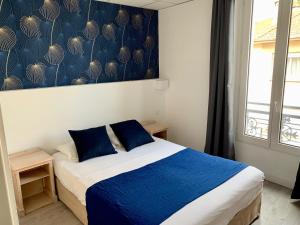 サン・ラファエルにあるオテル ド フロールのベッドルーム(青と白のベッド1台、窓付)