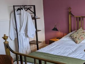 a bedroom with a bed with a robe hanging on a rack at Cowpers Oak in Olney