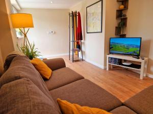 a living room with a couch and a flat screen tv at Dan Y Coed in Pont-Nedd-Fechan