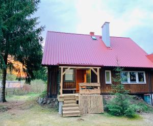a small wooden house with a red roof at Igły i szyszki in Zimna Woda
