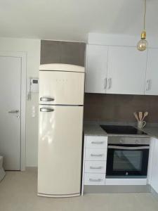 una cucina bianca con frigorifero e piano cottura di Ático duplex Do It Mediterranean a Vinarós Altre 18 foto