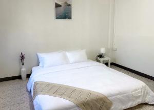 a bedroom with a white bed with a picture on the wall at MONTANA Hotel & Hostel Phuket in Karon Beach