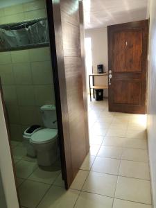 a bathroom with a toilet and a wooden door at Rivera Family Apartments in Santiago Este