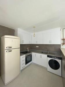 una cucina con mobili bianchi e un frigorifero bianco di Ático duplex Do It Mediterranean a Vinarós