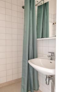 a bathroom with a sink and a green shower curtain at 2ndhomes Cozy Helsinki Center Studio with Park View in Helsinki