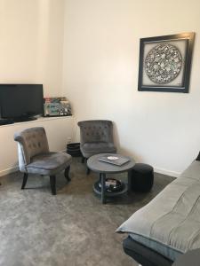 a living room with two chairs and a couch and a tv at Vue mer à Arromanches in Arromanches-les-Bains