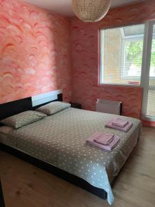 ルセにあるАПАРТАМЕНТ МИДИЯ ЕНОС РУСЕのピンクの壁、ベッド1台付きのベッドルーム1室