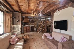 ein Wohnzimmer mit einem Sofa und einem Flachbild-TV in der Unterkunft La Cantina casas rurales paredes in Villar de Corneja