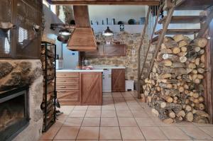 a kitchen with wooden cabinets and a fireplace at La Cantina casas rurales paredes in Villar de Corneja