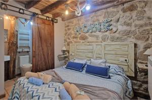 1 dormitorio con 1 cama grande con almohadas azules en La Cantina casas rurales paredes en Villar de Corneja