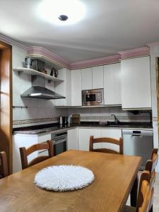 una cocina con mesa de madera y una cocina con armarios blancos. en Arotzetxea, en Elizondo