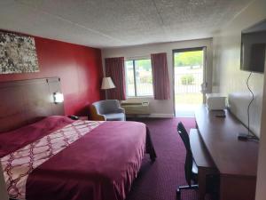 チェサピークにあるAmerican Inn Chesapeake - Portsmouthのベッドとデスクが備わるホテルルームです。