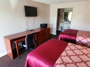 チェサピークにあるAmerican Inn Chesapeake - Portsmouthのベッド2台、デスク、テレビが備わるホテルルームです。