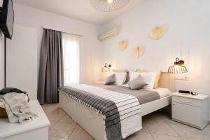 a white bedroom with a bed and a window at Erato Inn Naxos in Agios Prokopios