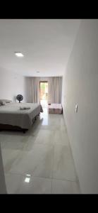 a white bedroom with a bed and a large window at Casa Malta - St Sul in Goiânia