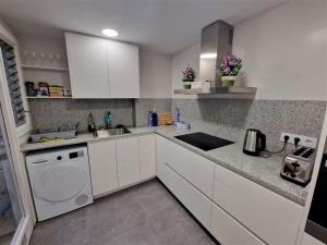 cocina con armarios blancos, fregadero y lavavajillas en París Habitaciones en Barcelona