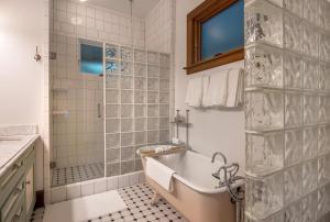 une salle de bain blanche avec une baignoire et une douche dans l'établissement Historic Roe Parker home, à Hood River