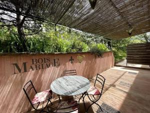 eine Terrasse mit Tisch und Stühlen und ein Schild in der Unterkunft Gîtes Bois-Mariage in Veaux