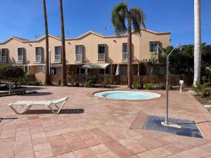 un edificio con piscina e panchina in un cortile di VILLA LUZ SUITE a Maspalomas