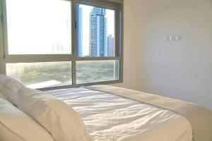 Cama blanca en habitación con ventana grande en Brand New Flat Seaview 4BDR 140m2, en Netanya