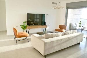 uma sala de estar com um sofá, uma mesa e cadeiras em Brand New Flat Seaview 4BDR 140m2 em Netanya