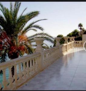 una recinzione bianca con palme sullo sfondo di Villa (Palace) Unique avec plage privée a Santa Faz