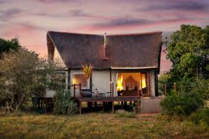 a small white house with a large roof at Bush Lodge – Amakhala Game Reserve in Amakhala Game Reserve
