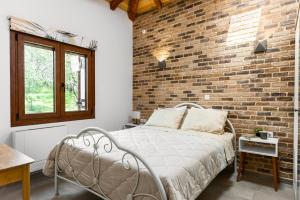 Un dormitorio con una pared de ladrillo y una cama en Eloise Apartments, en Ágios Matthaíos